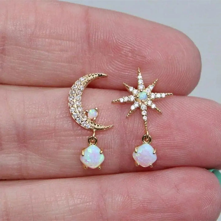 Detaljeret billede af kvinders dingle øreringe: gylden måne og stjerne med iriserende opal sten.