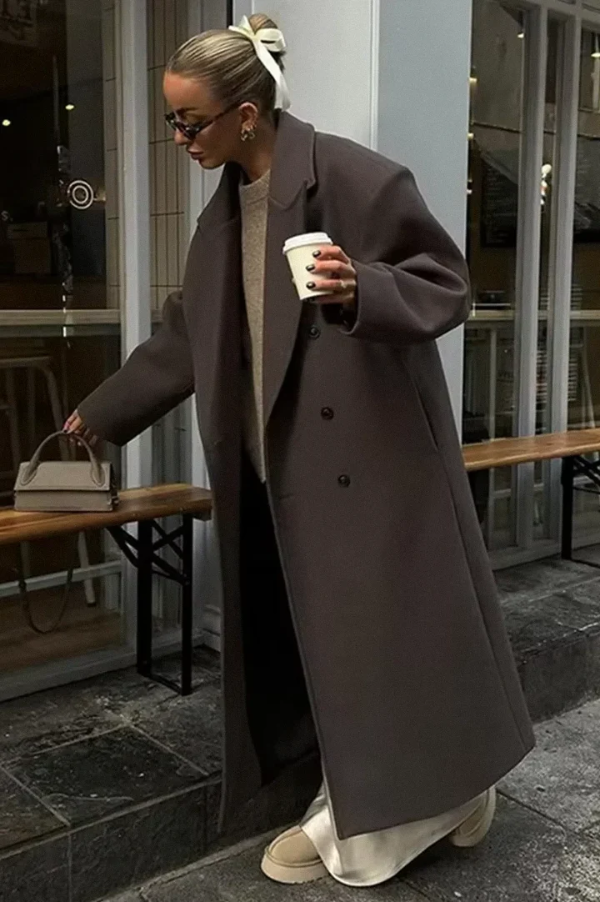 Lang, elegant, brun dame vinterfrakke med klassisk dobbeltradet lukning. Tidløs stilfuld overtøj til damemode.