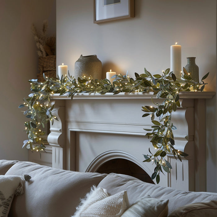 Nærbillede af LED lyskæde med detaljerede olivenblade og blødt, varmhvidt lys. Perfekt til hygge.