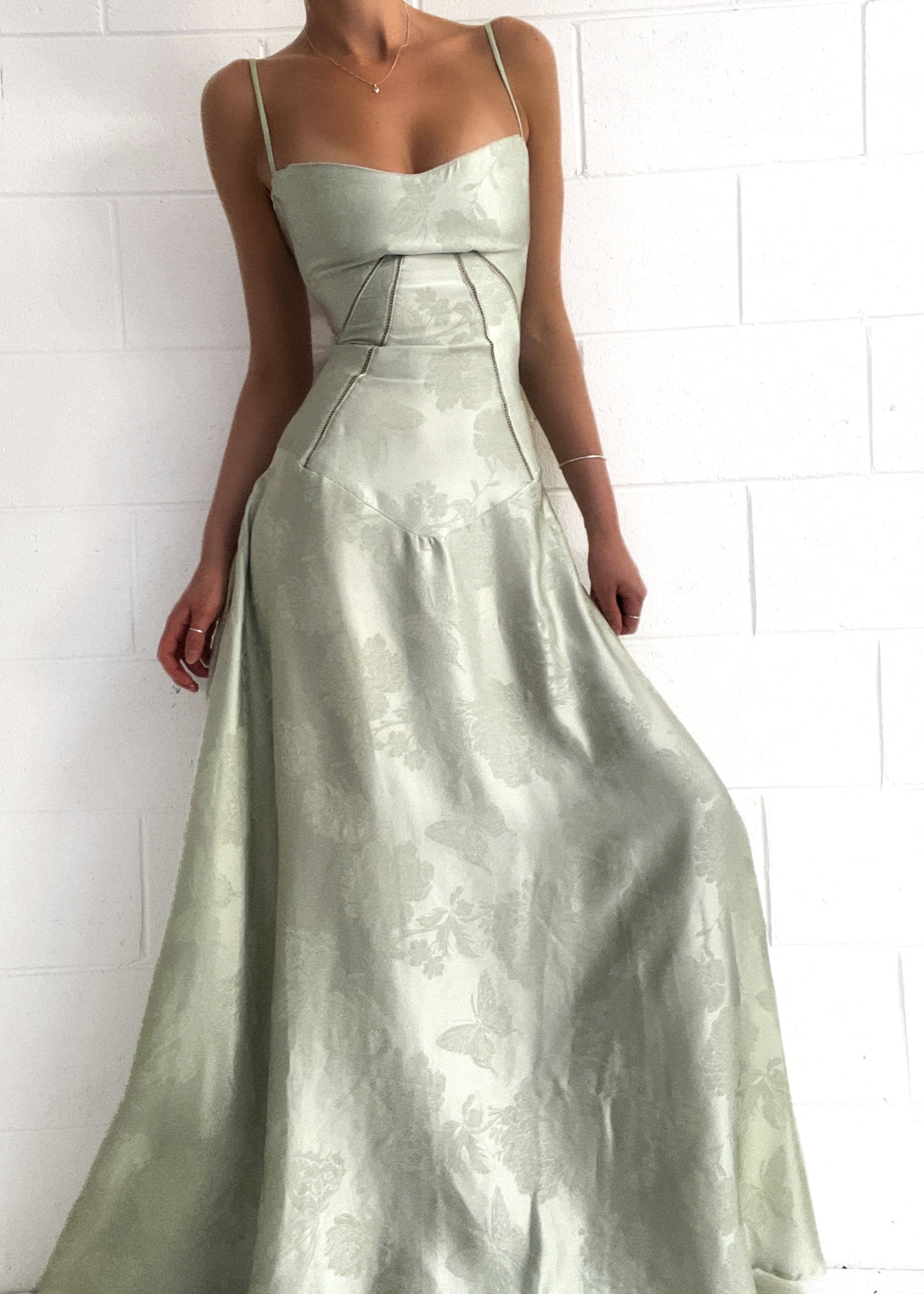 Model bærer lysegrøn stropløs satinkjole, lang og elegant til galla.