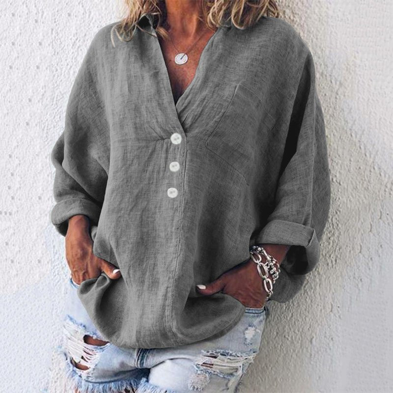 Grå V-hals oversize sommerbluse i hør, med rulleærmer og knaplukning. Løs og elegant pasform.