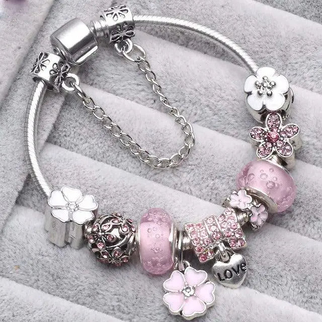 Lyserødt charm armbånd til kvinder med elegante blomster og perler. Et feminint damearmbånd, perfekt gave.