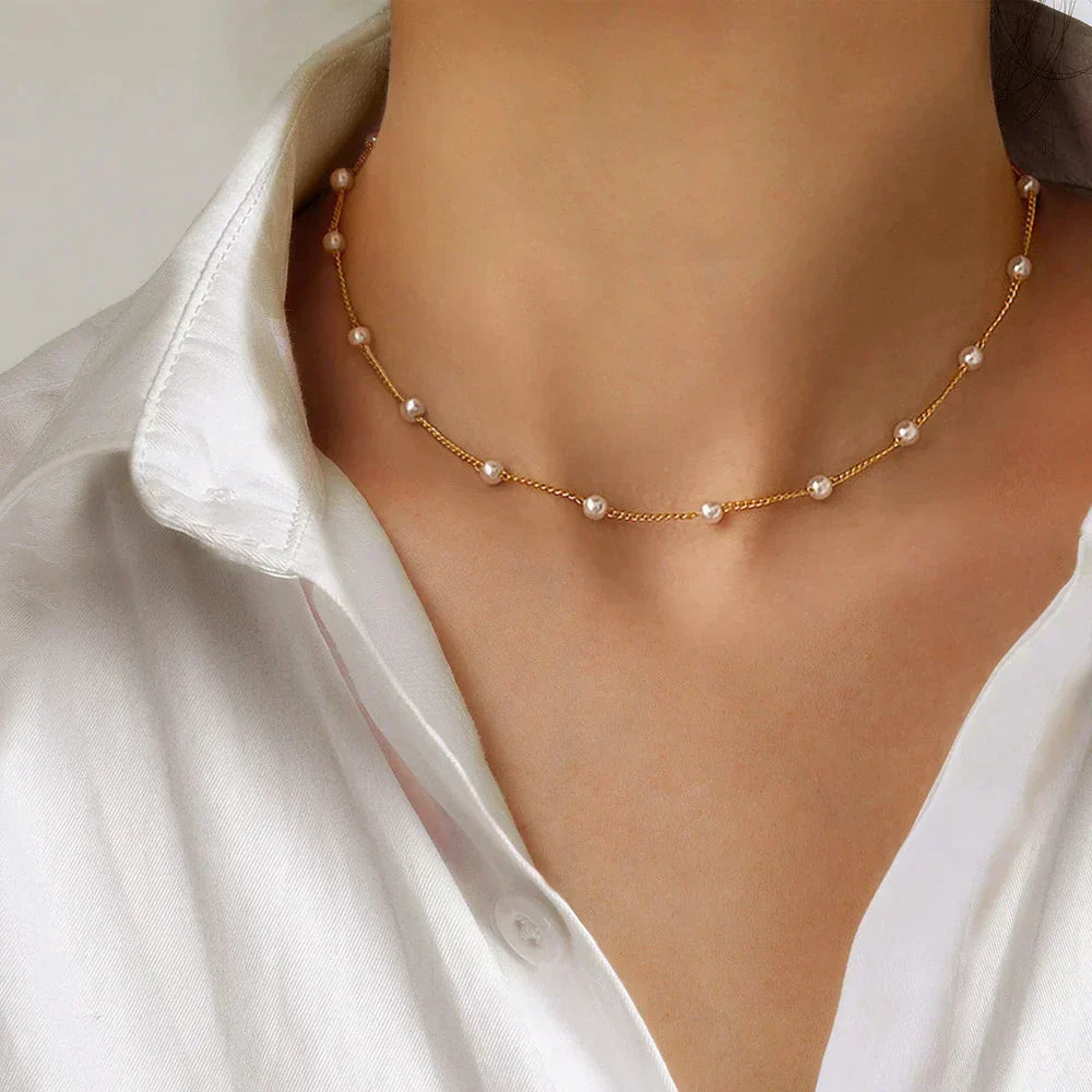 Minimalistisk guld choker halskæde med små hvide perler. Elegant damehalskæde til hverdag eller fest.