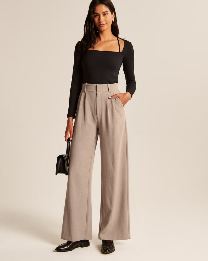 "Model iført beige polyester bukser med høj talje og bredde ben, ideel til professionelt og tidløst look."