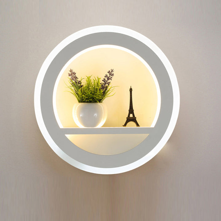 Elegant LED-væglampe med rundt design og integreret hylde, ideel som stuebelysning eller soveværelseslampe.