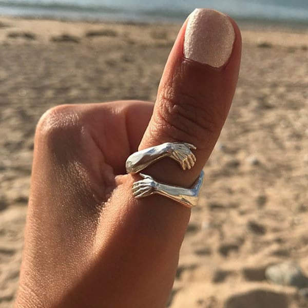 Sølv krammering med to hænder der omfavner fingeren, justerbar dame ring, symboliserer kærlighed og forbindelse.