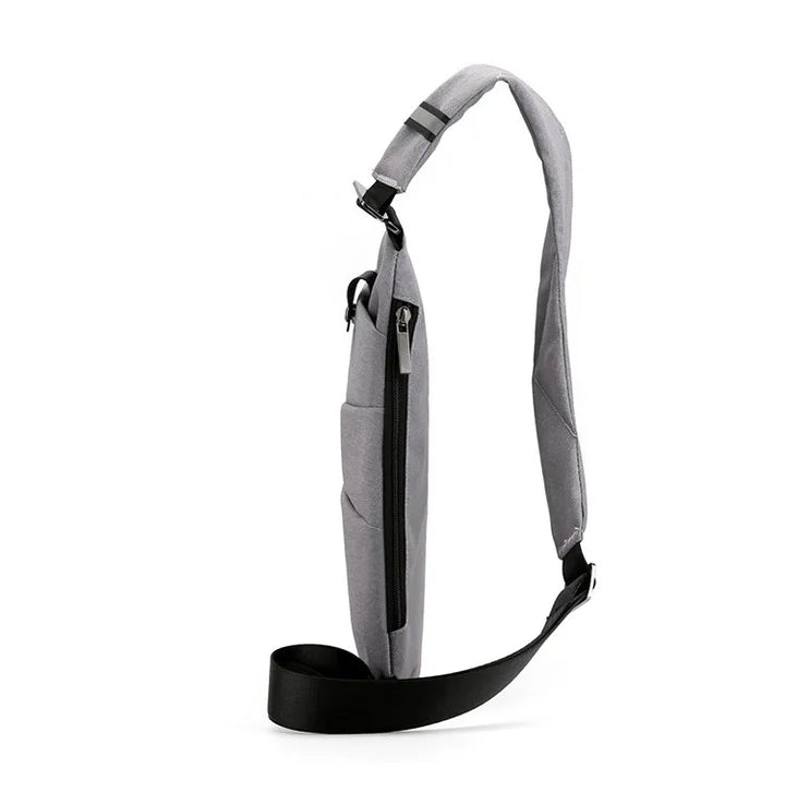 Grå mini crossbody taske med justerbar rem, tyverisikker og praktisk til eventyr eller daglig brug.